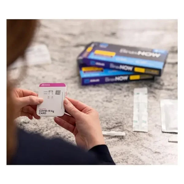 woman holding a BinaxNow Covid-19 Antigen Self Test kits